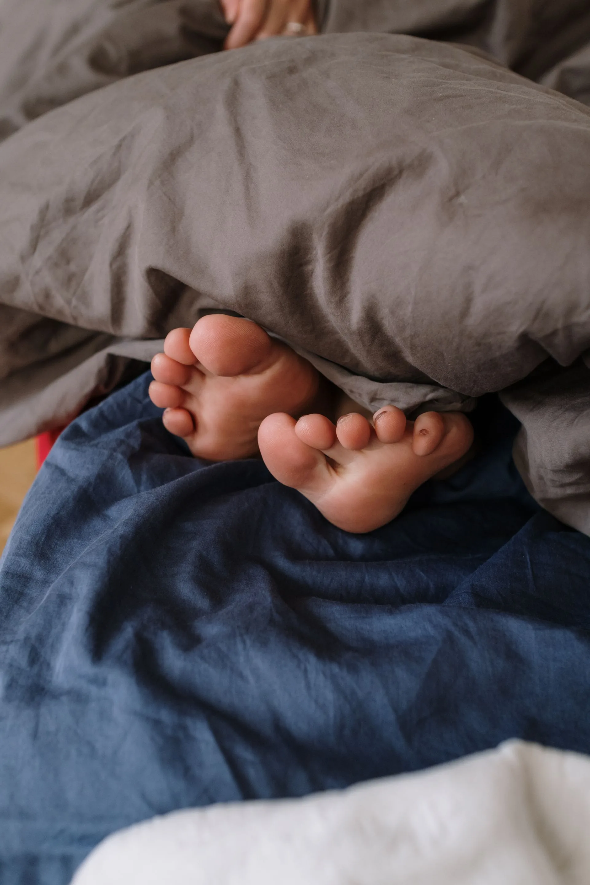 Cozy bed with soft linens, feet peeking out from under a folded blanket