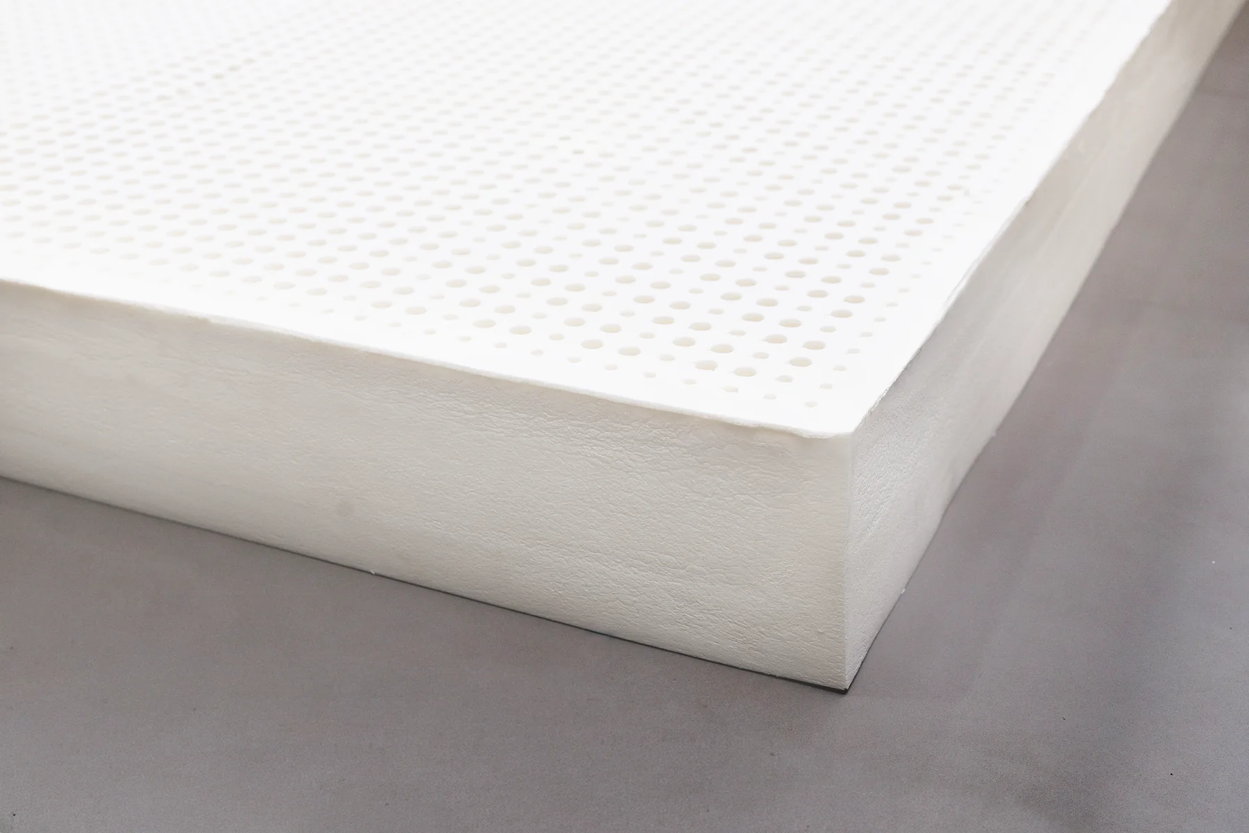 Natural latex mattress topper resting on the floor, showing its full size